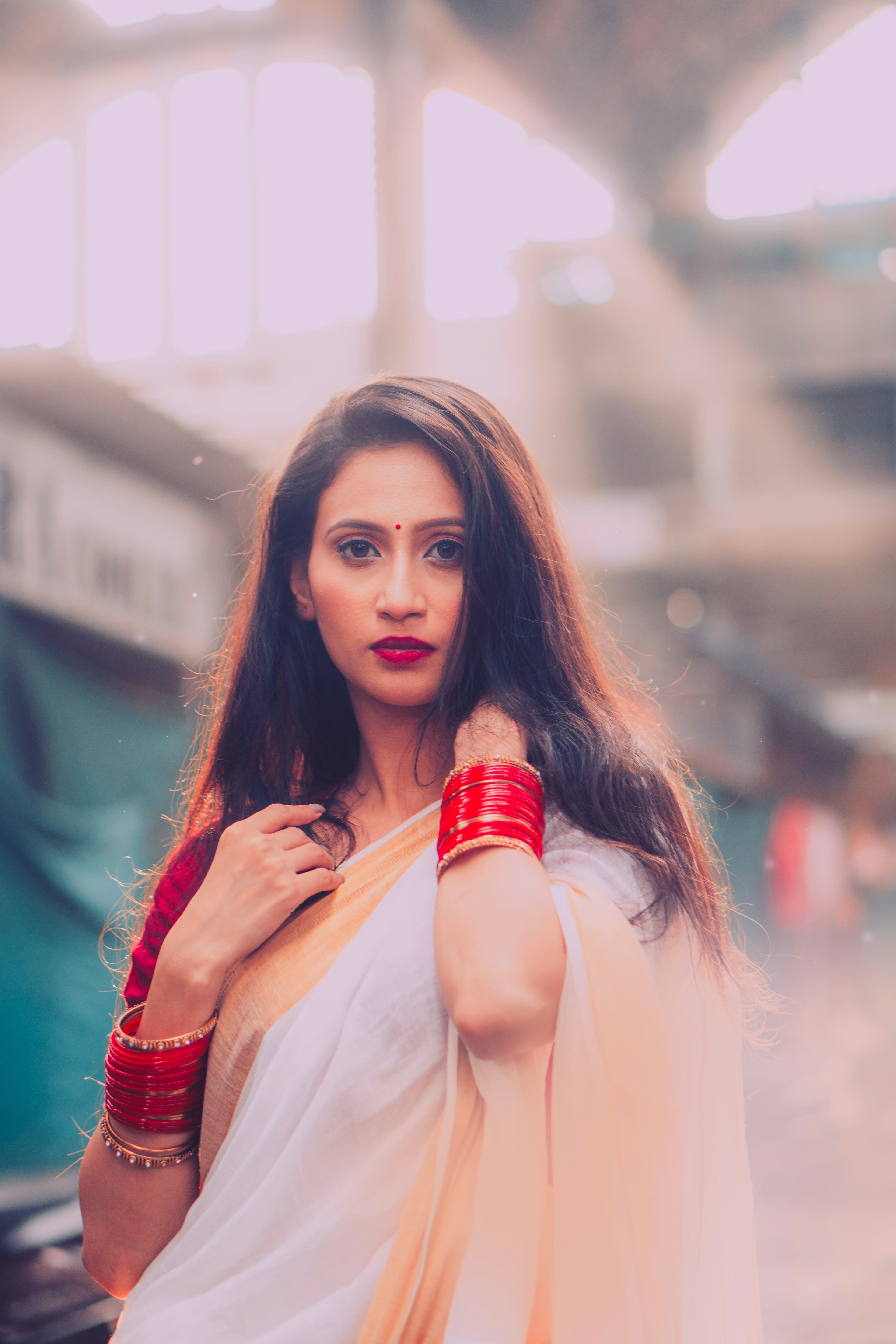 Woman in an ivory and peach saree with red bangles