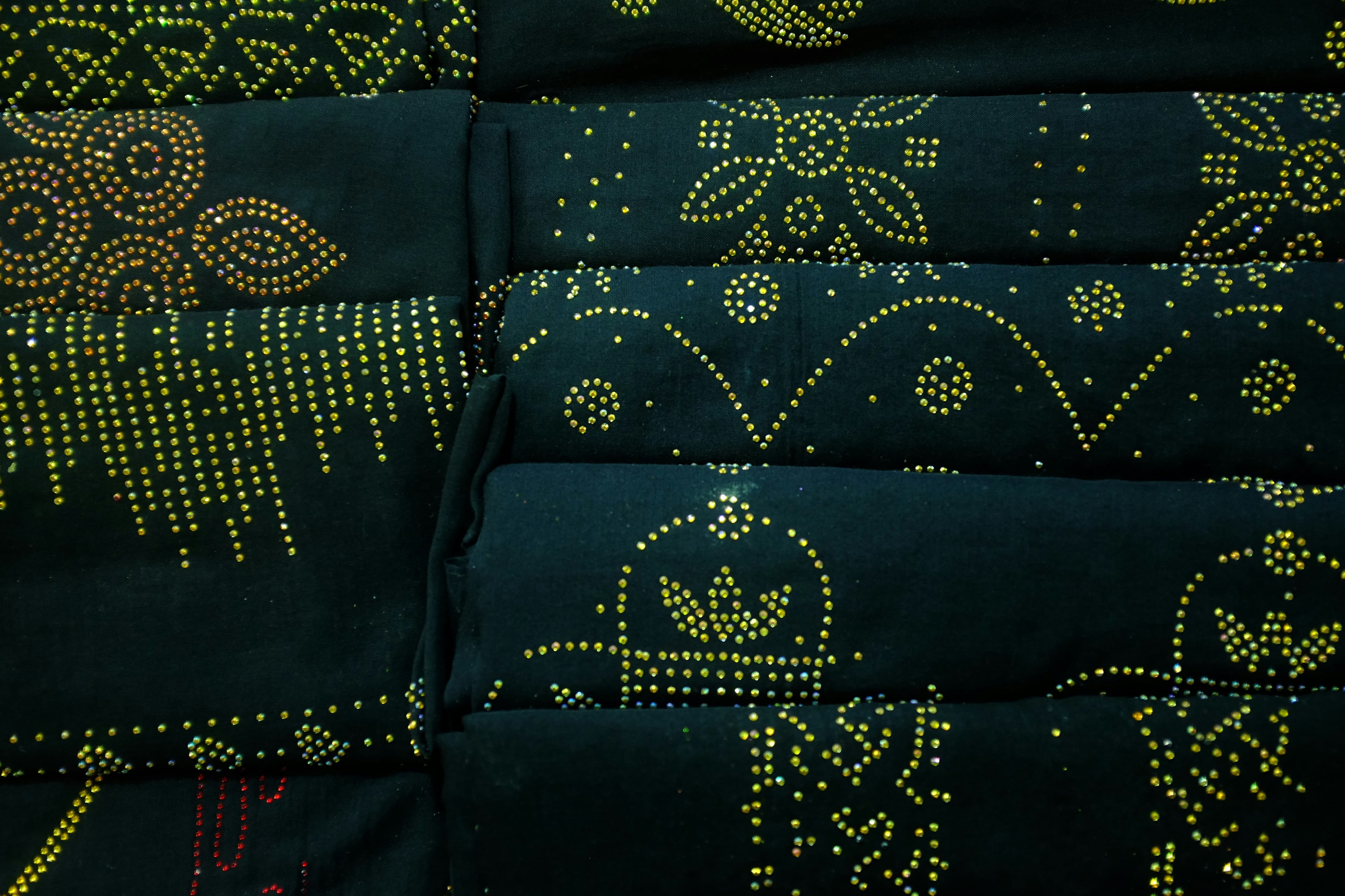 Dark fabric embellished with fine gold beadwork motifs