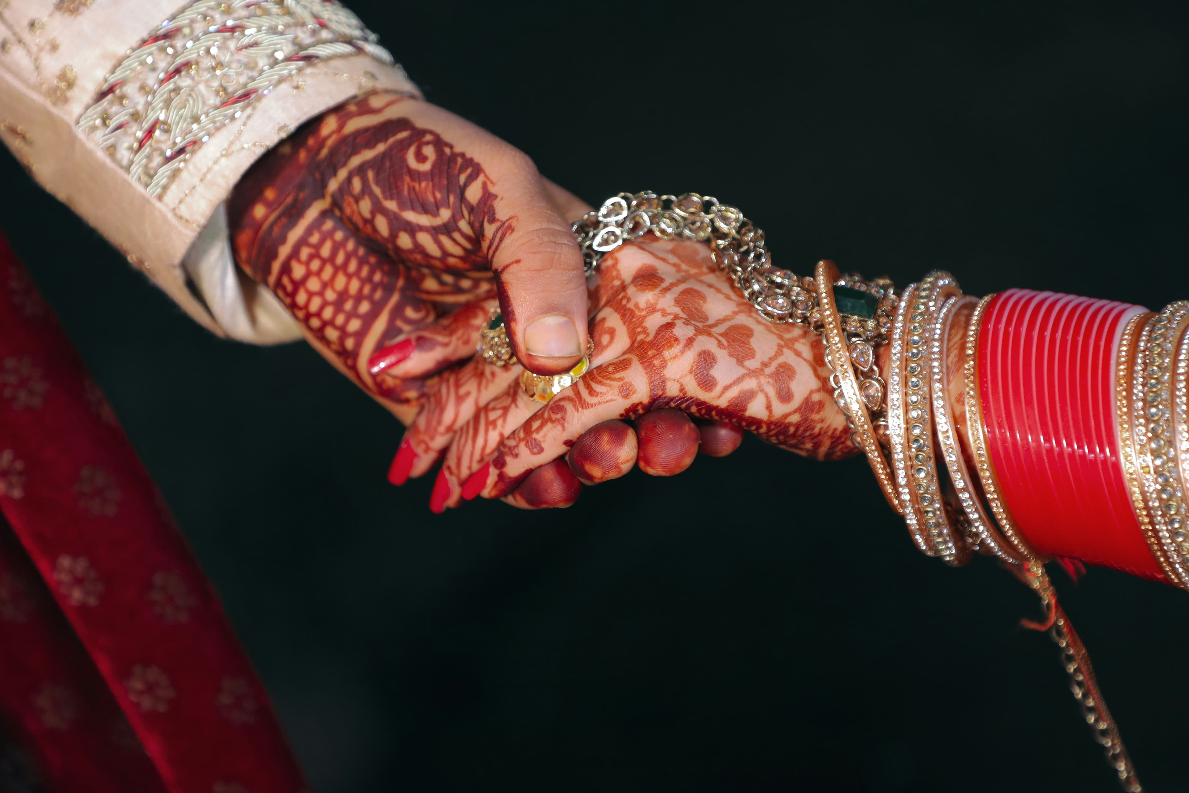 Mehendi-covered hands with red chura bangles held together