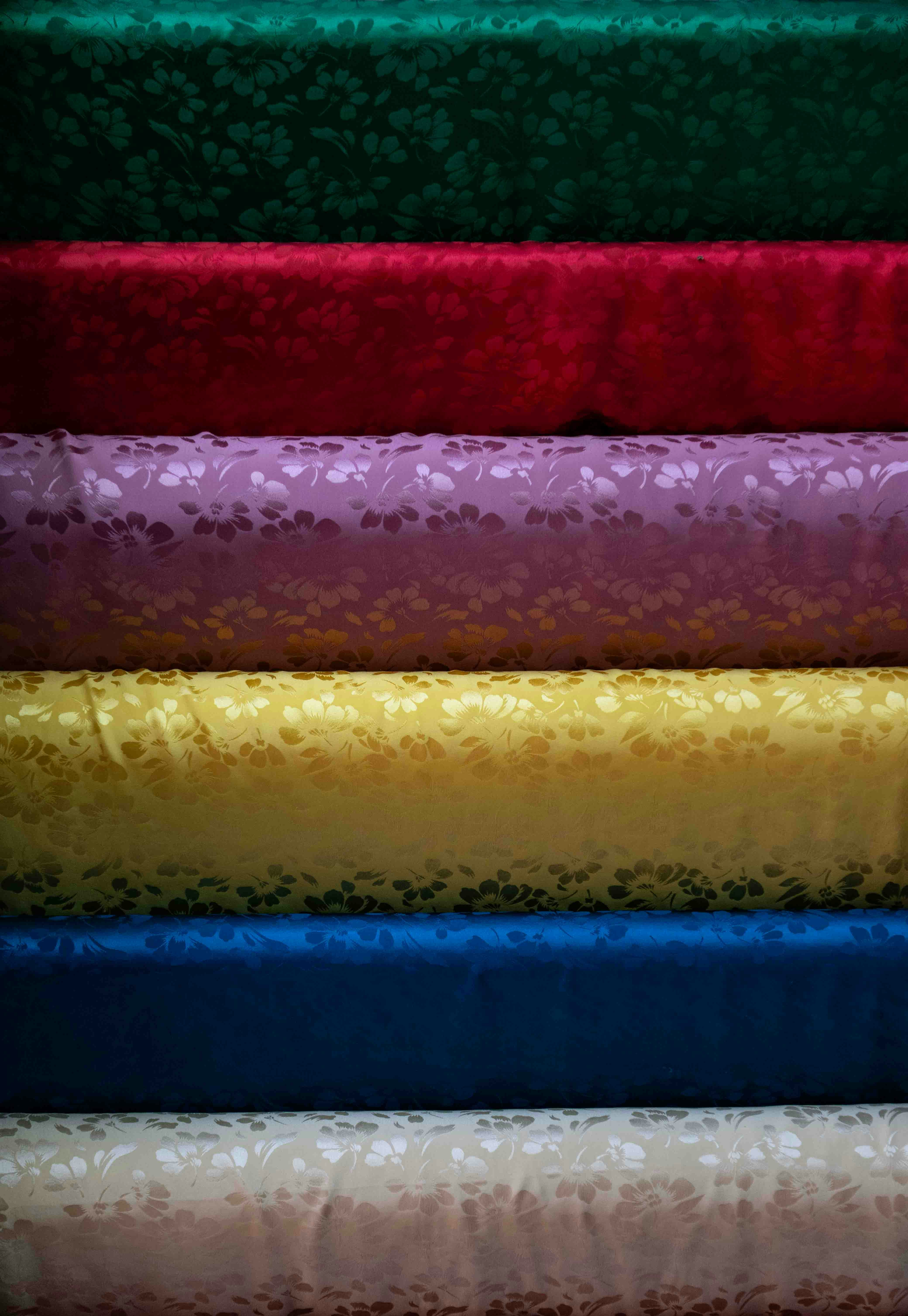 Stacked rolls of jacquard silk fabric in jewel colours