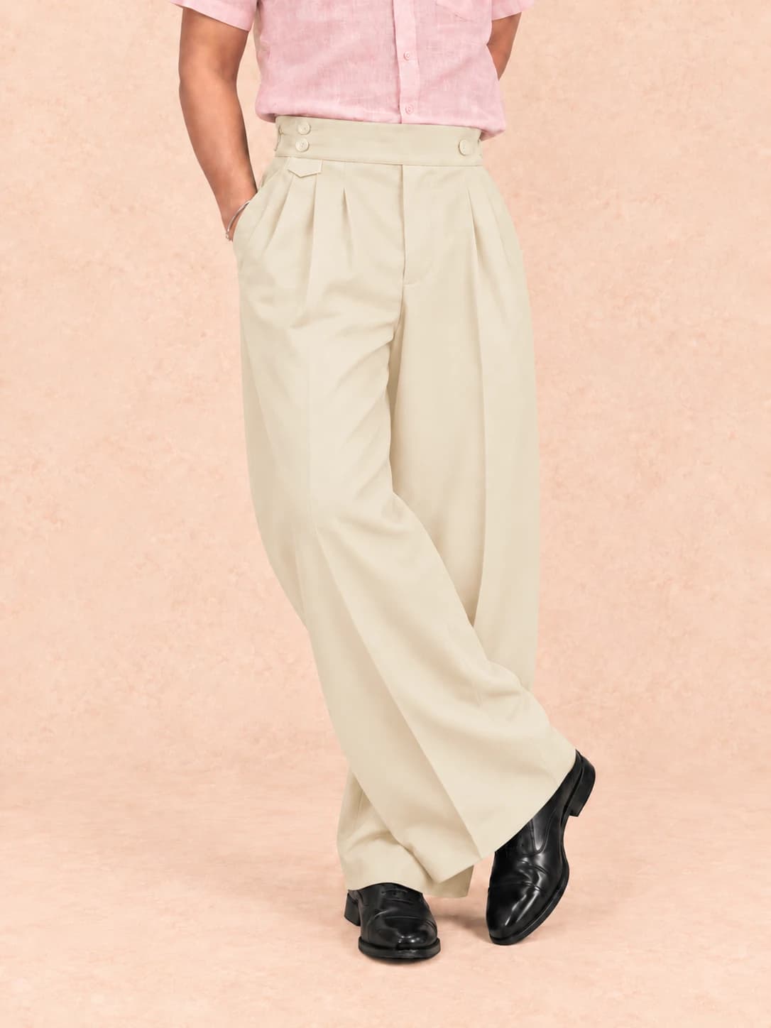 Cream pleated trousers — full-length view, standing cross-legged