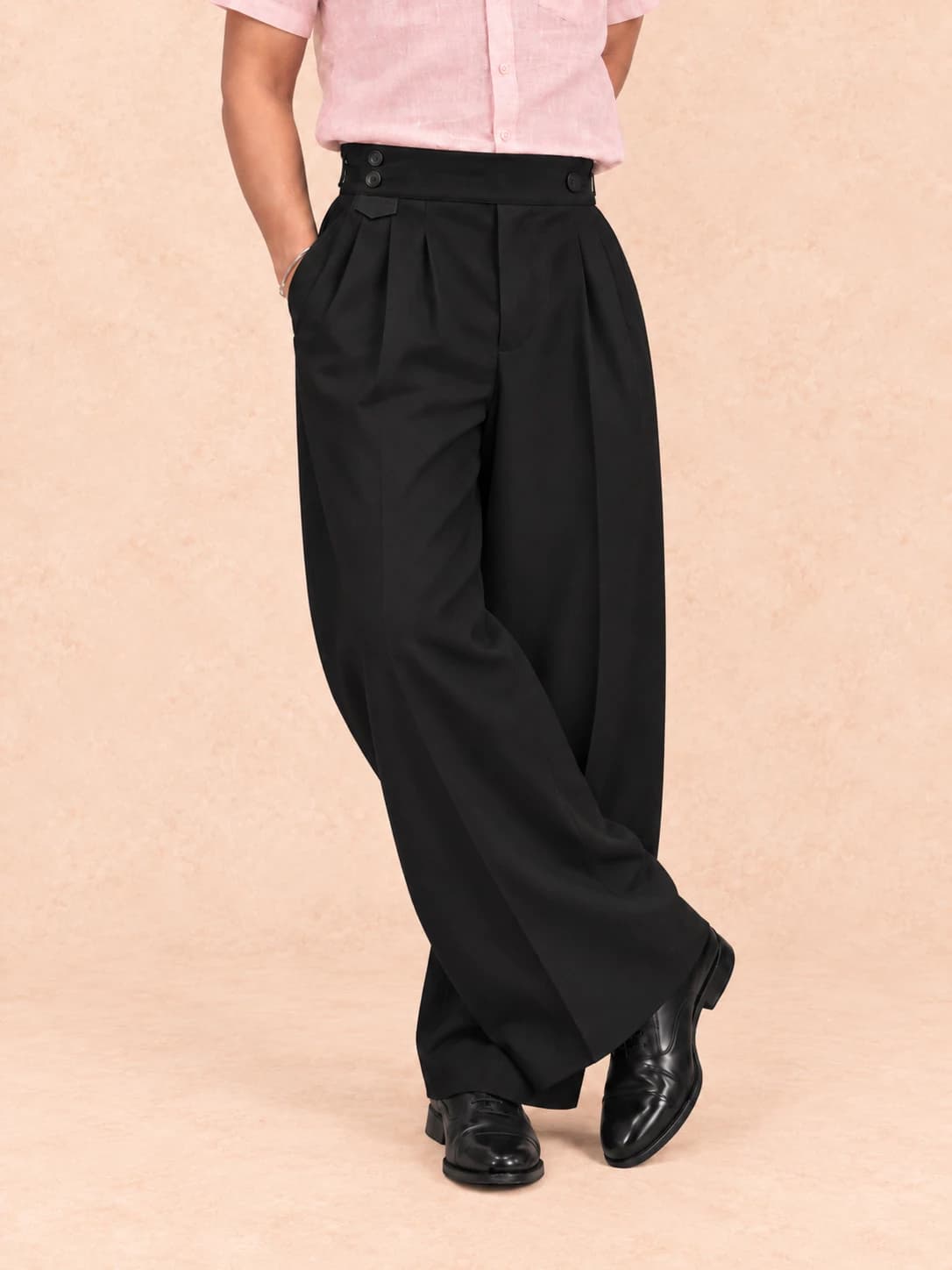 Black pleated trousers — full-length view, standing cross-legged
